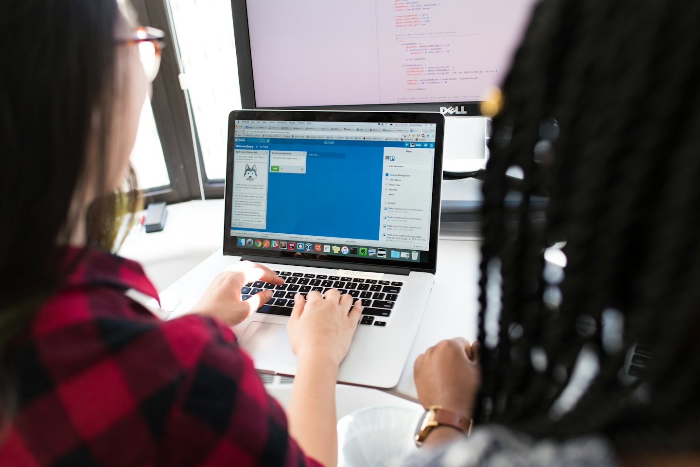 Dos compañeros de trabajo colaborando en un portátil con Trello.