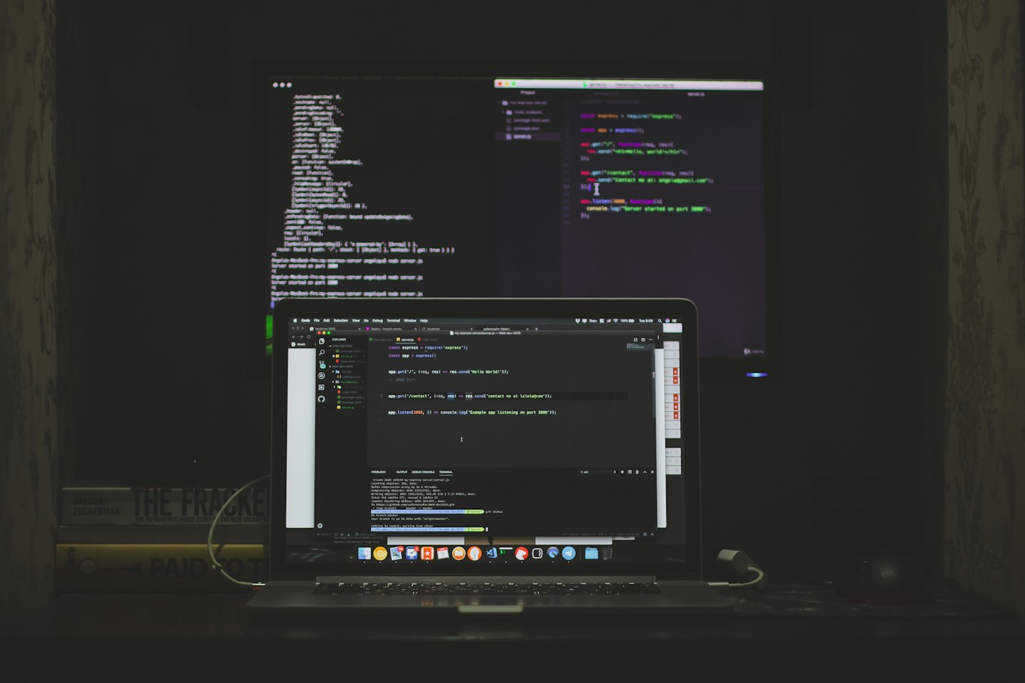 Portátil y monitor externo mostrando código en un escritorio.